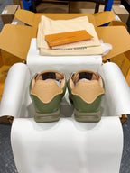 Green leather sneakers with tan heel tabs and white laces in shoebox