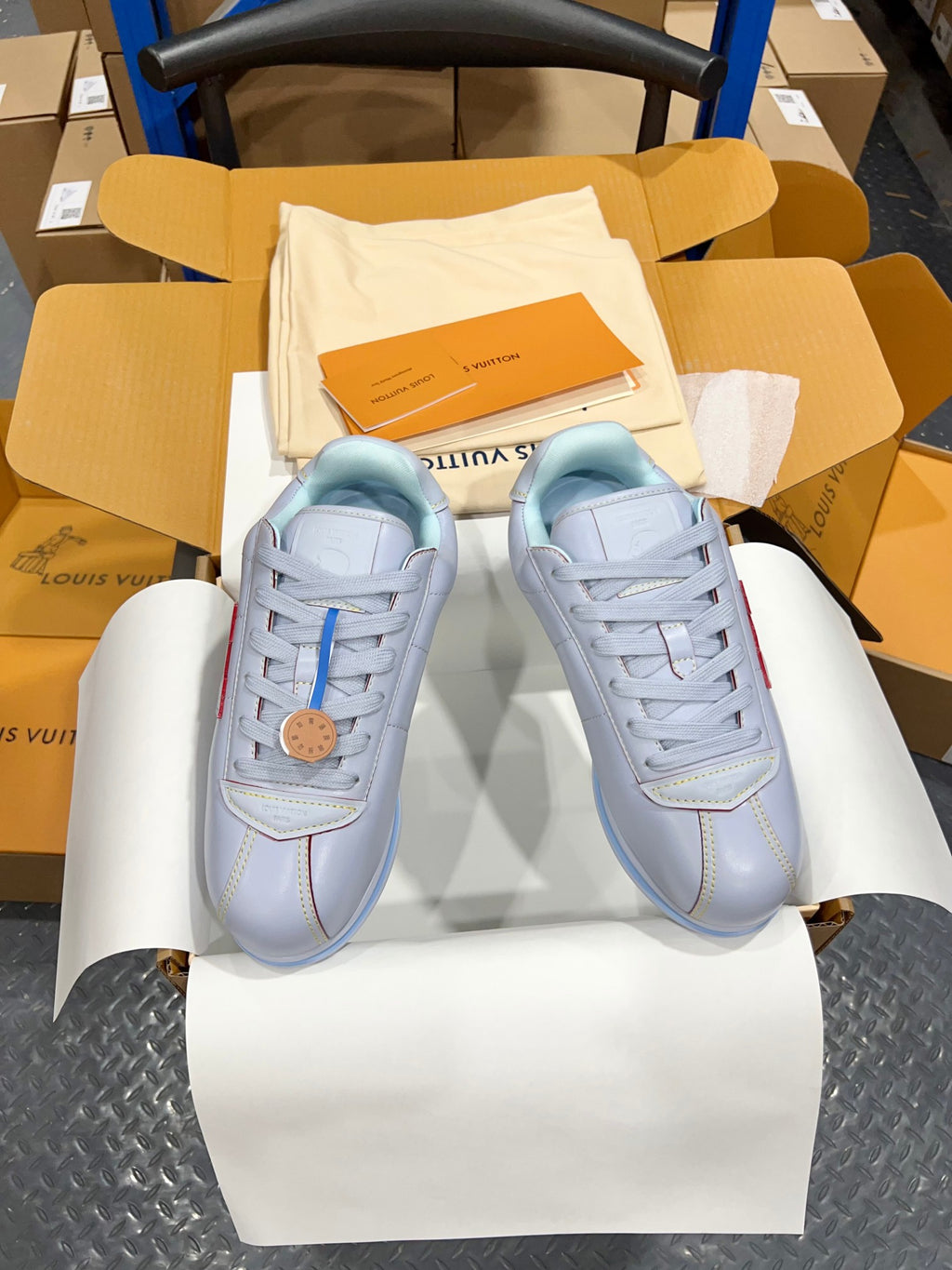Two light blue sneakers with lace-up closure, logo patch, and blue rubber sole