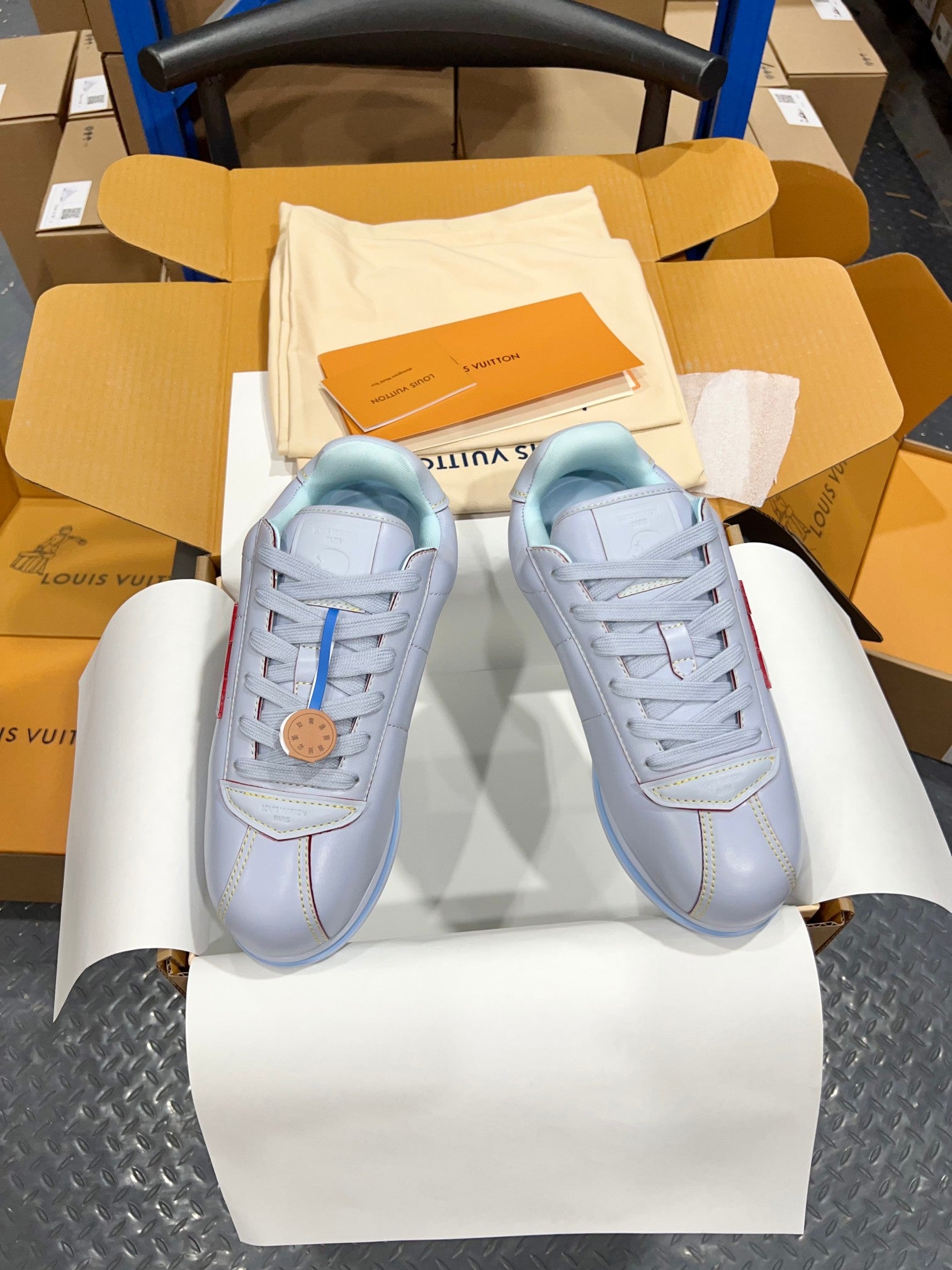 Two light blue sneakers with lace-up closure, logo patch, and blue rubber sole