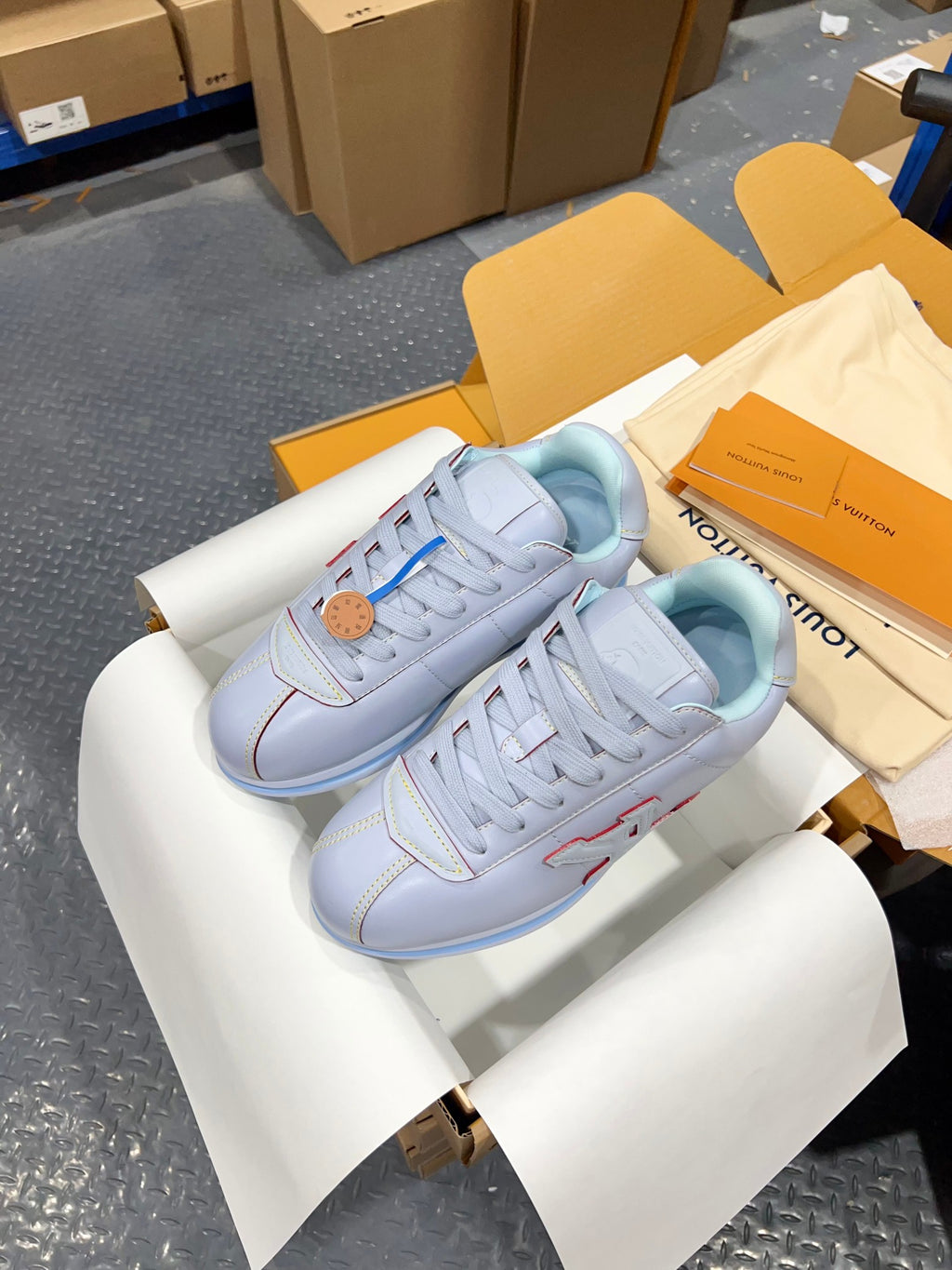 Light blue lace-up sneakers in open box with blue outsole and side logo panel