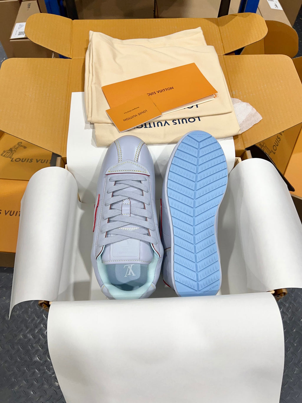 Light blue sneaker showing treaded blue sole and lace-up upper in box