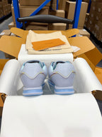 Back view of light blue sneakers with blue striped soles in display box