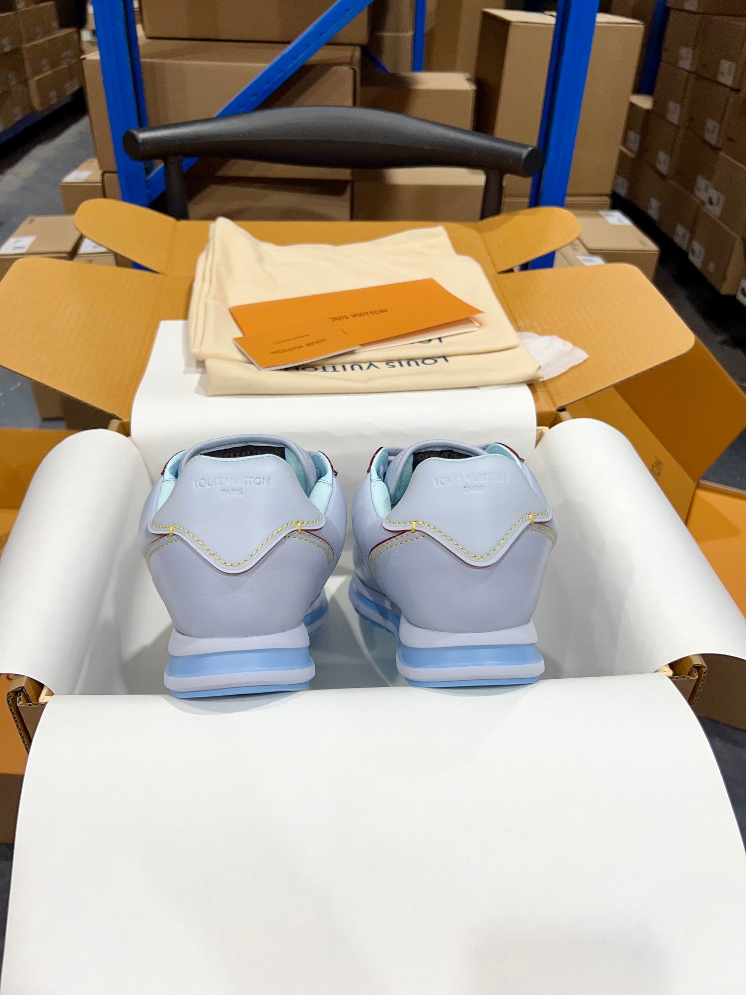 Back view of light blue sneakers with blue striped soles in display box