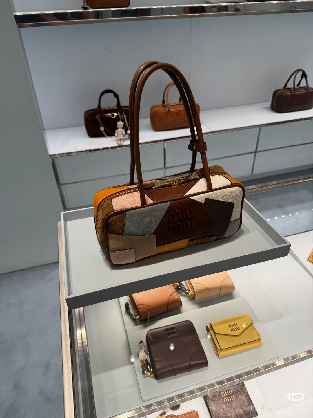 Patchwork leather bag on display with top handles, multicolor front panels, and visible zip detail.