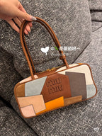 Patchwork leather bag with top handles, brown trim, and multicolor block panels in cream, blue, and orange.