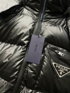 Black long puffer jacket detail with hanging tag and Prada logo patch