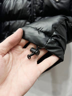 Black puffer sleeve cuff detail with snap and small strap hardware
