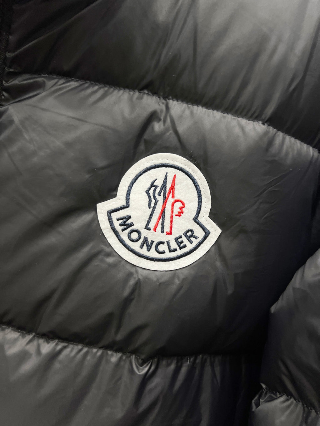 Moncler logo patch on dark quilted puffer jacket