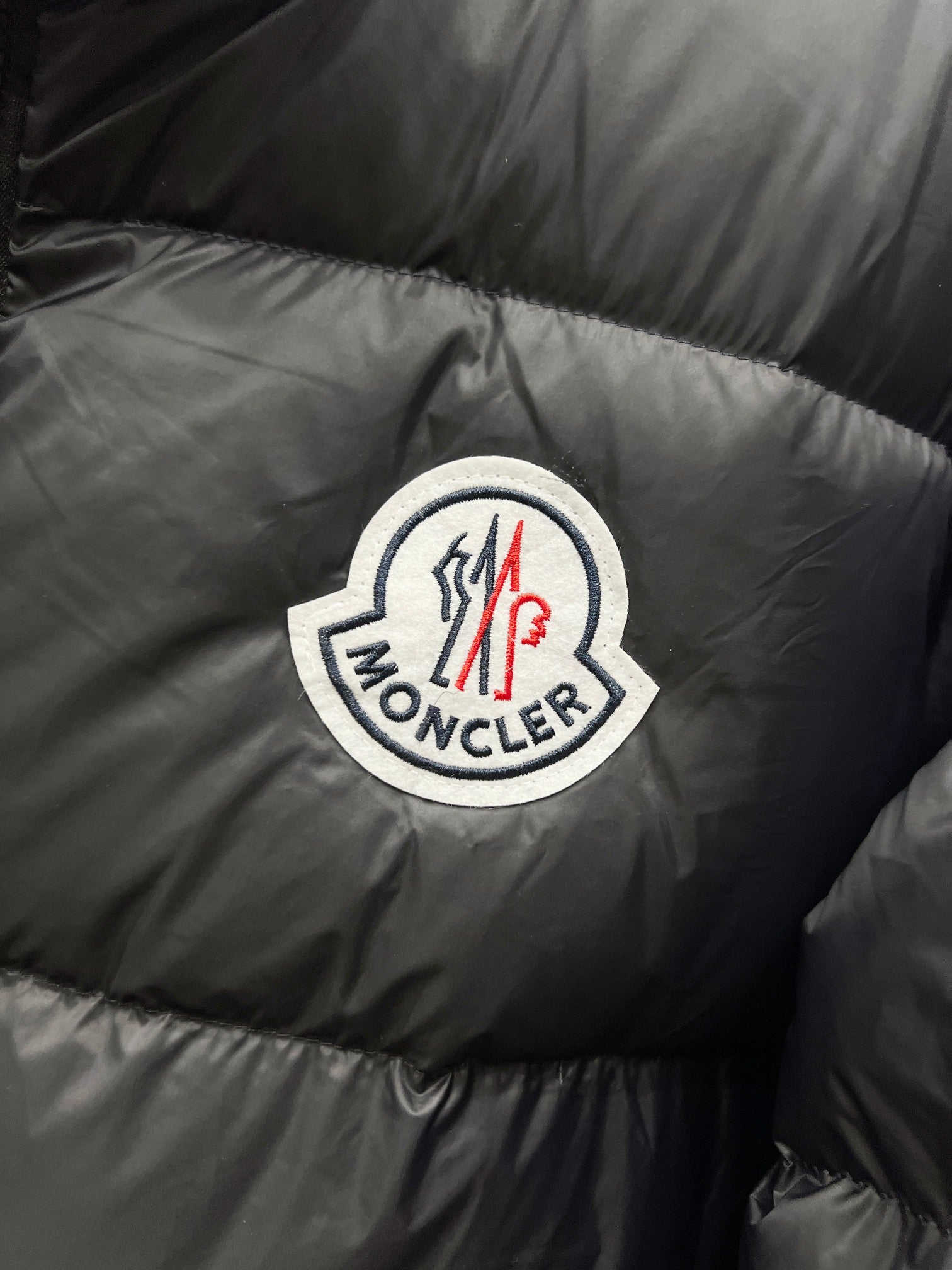 Moncler logo patch on dark quilted puffer jacket