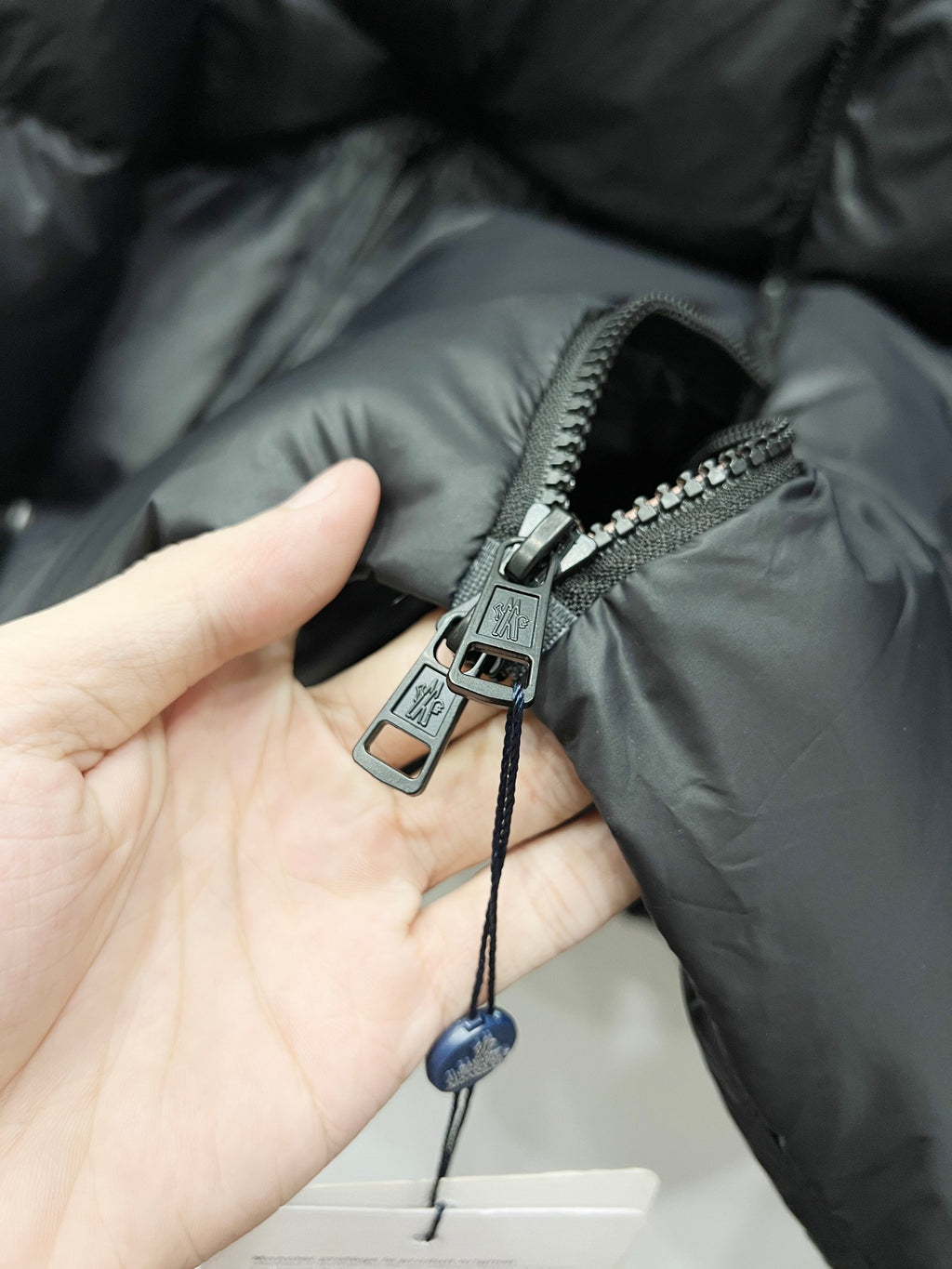 Dark puffer jacket zipper pull and slider with fabric strap detail