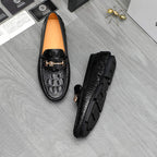 Black leather loafers with embossed pattern and gold-tone buckle, side view and sole.
