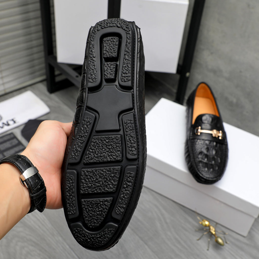 Black loafer bottom view with treaded sole and embossed grip pattern.