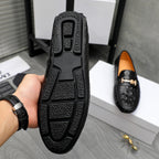 Black loafer bottom view with treaded sole and embossed grip pattern.