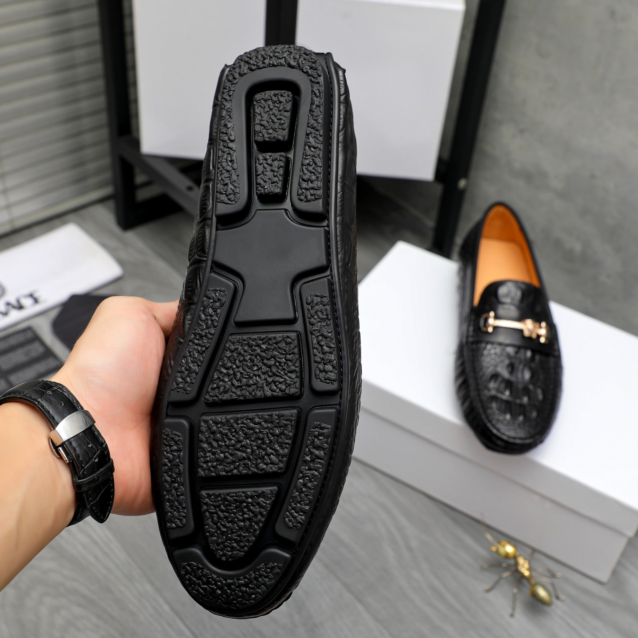 Black loafer bottom view with treaded sole and embossed grip pattern.