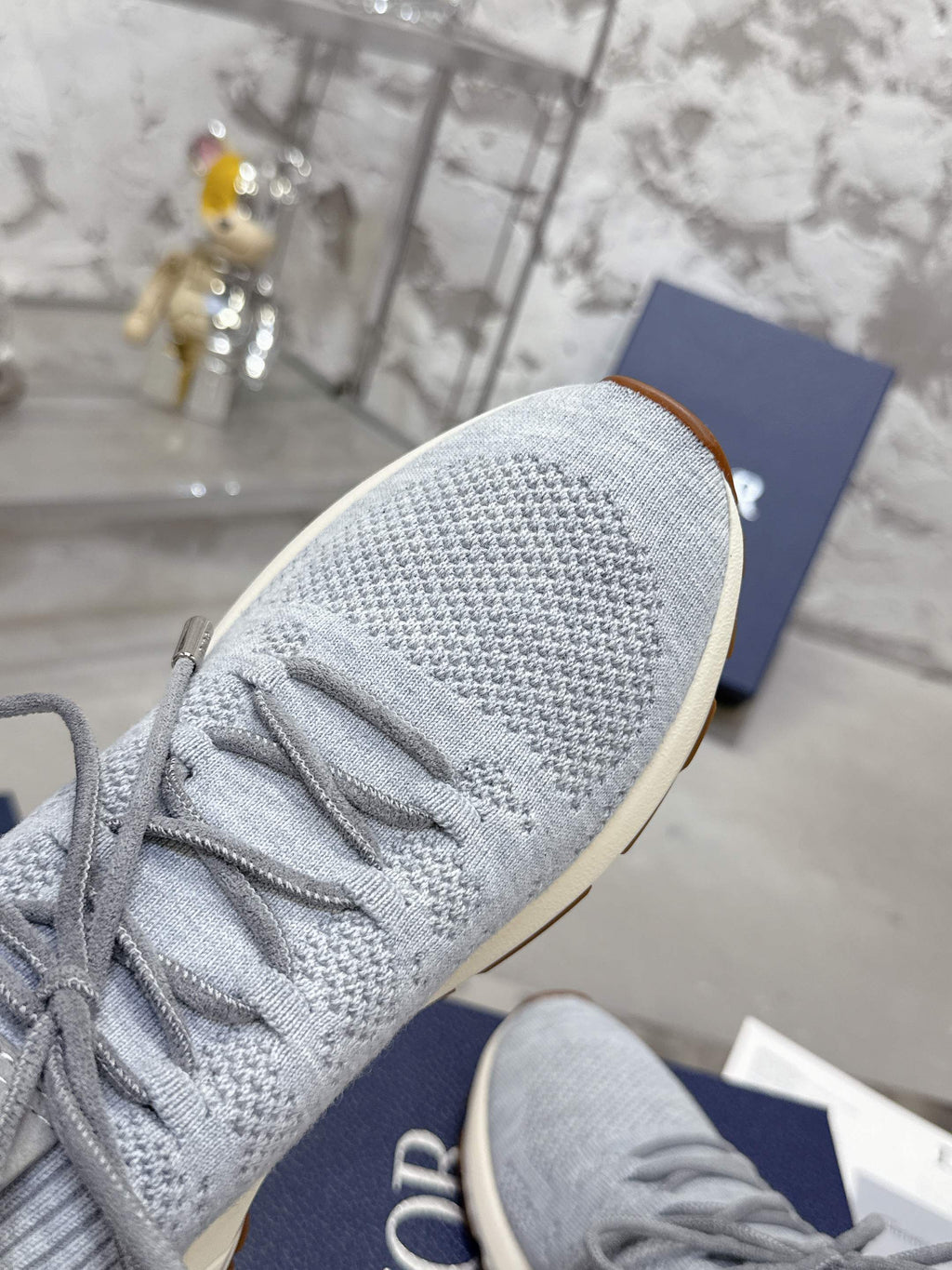 Light gray knit sneaker side profile with tan rubber sole and white laces