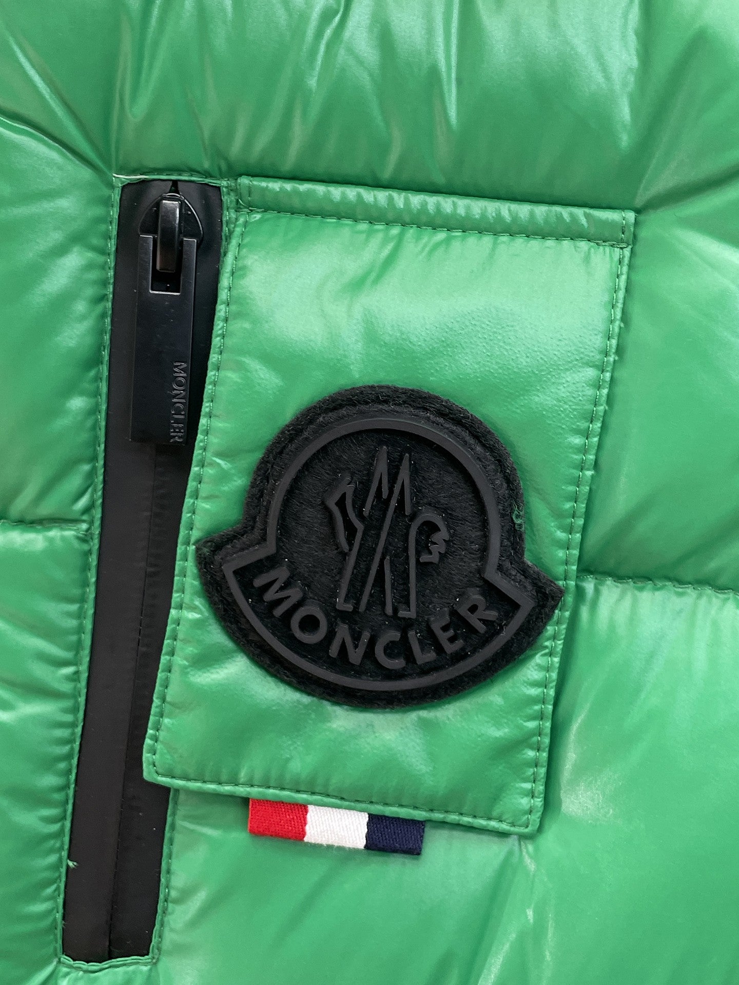 Green puffer vest chest patch with black circular Moncler logo on pocket