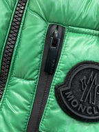 Green puffer vest close-up of zipper and black circular Moncler logo patch