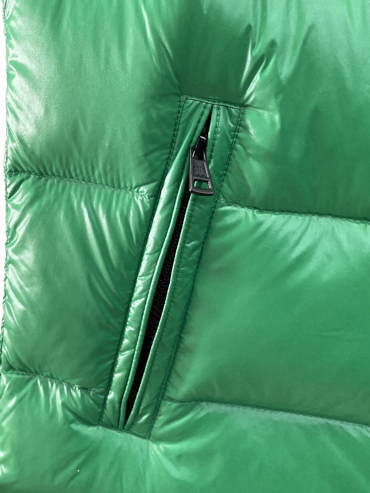 Green puffer vest lower front section with vertical zipper and small label