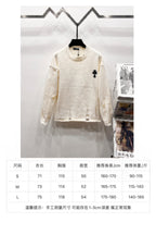 Cream long-sleeve knit sweater on hanger with small black clover emblem on chest