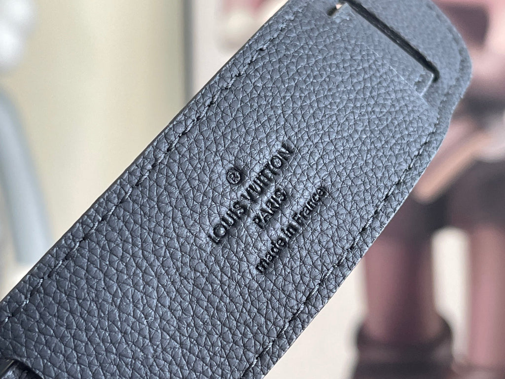 Louis Vuitton bag strap close-up with embossed logo text on textured leather.