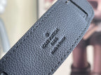Louis Vuitton bag strap close-up with embossed logo text on textured leather.