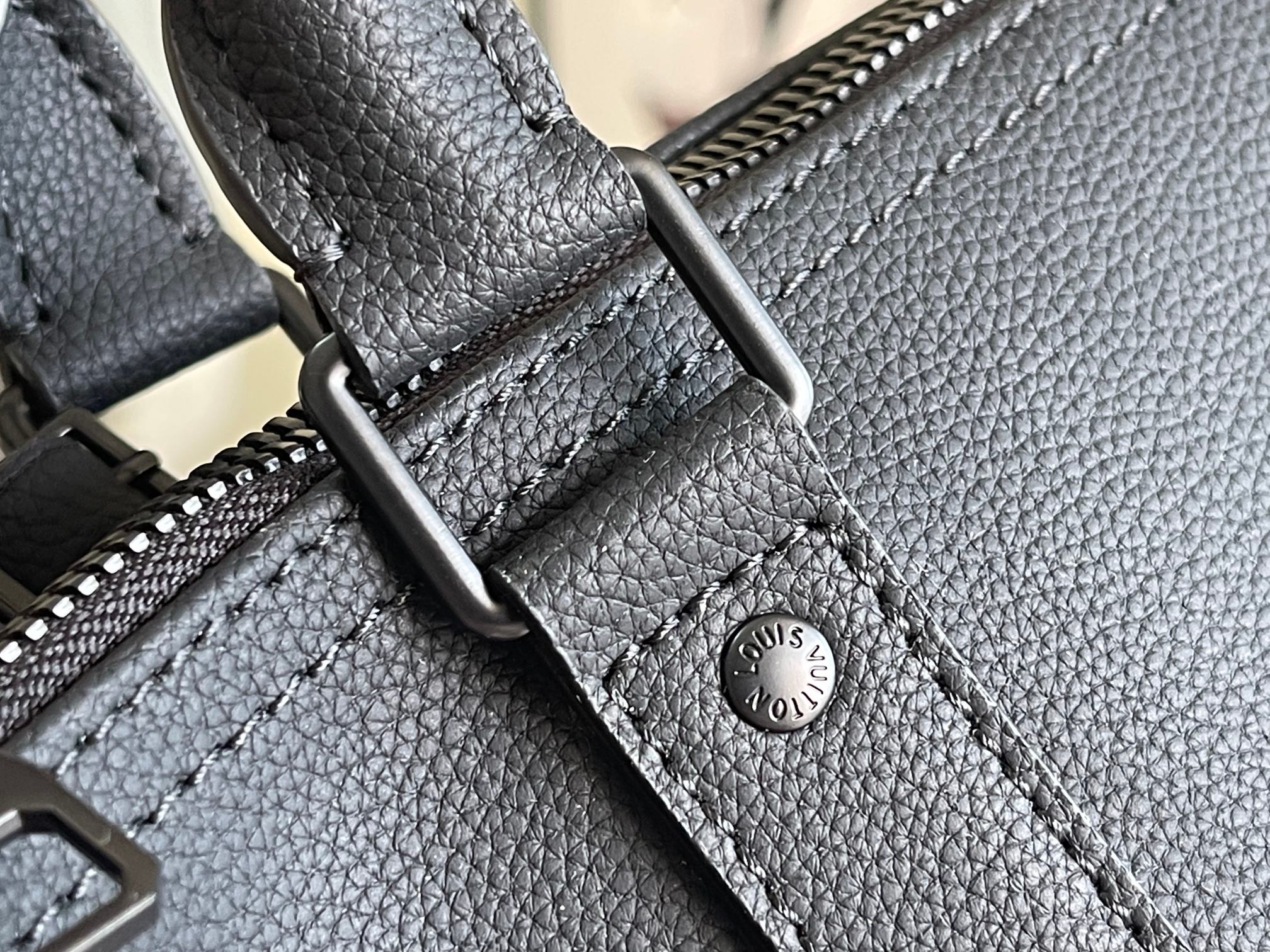 Louis Vuitton duffel bag close-up of textured leather, stitching, and logo stamp
