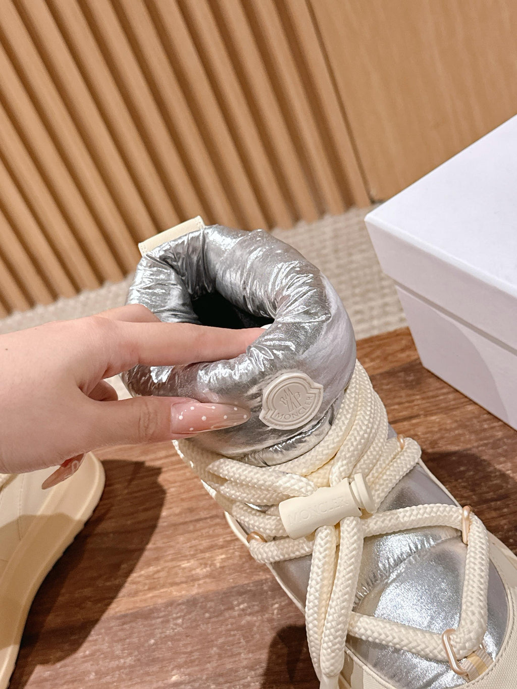 Moncler lace-up sneaker boot with silver padded collar and cream laces, hand holding