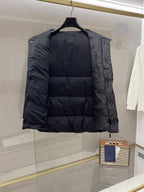 Dark long puffer vest with open side and buttoned strap at the armhole