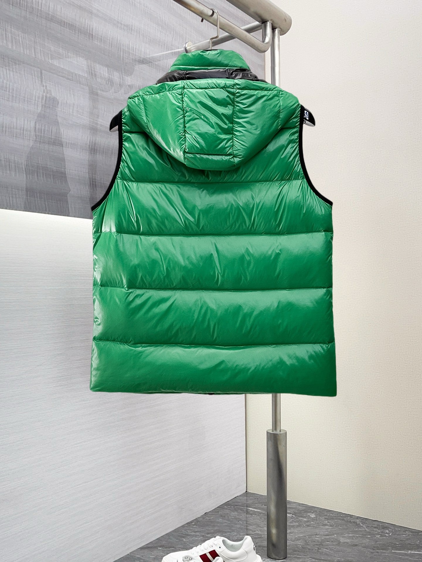 Green hooded puffer vest, back view with horizontal quilting and zipper