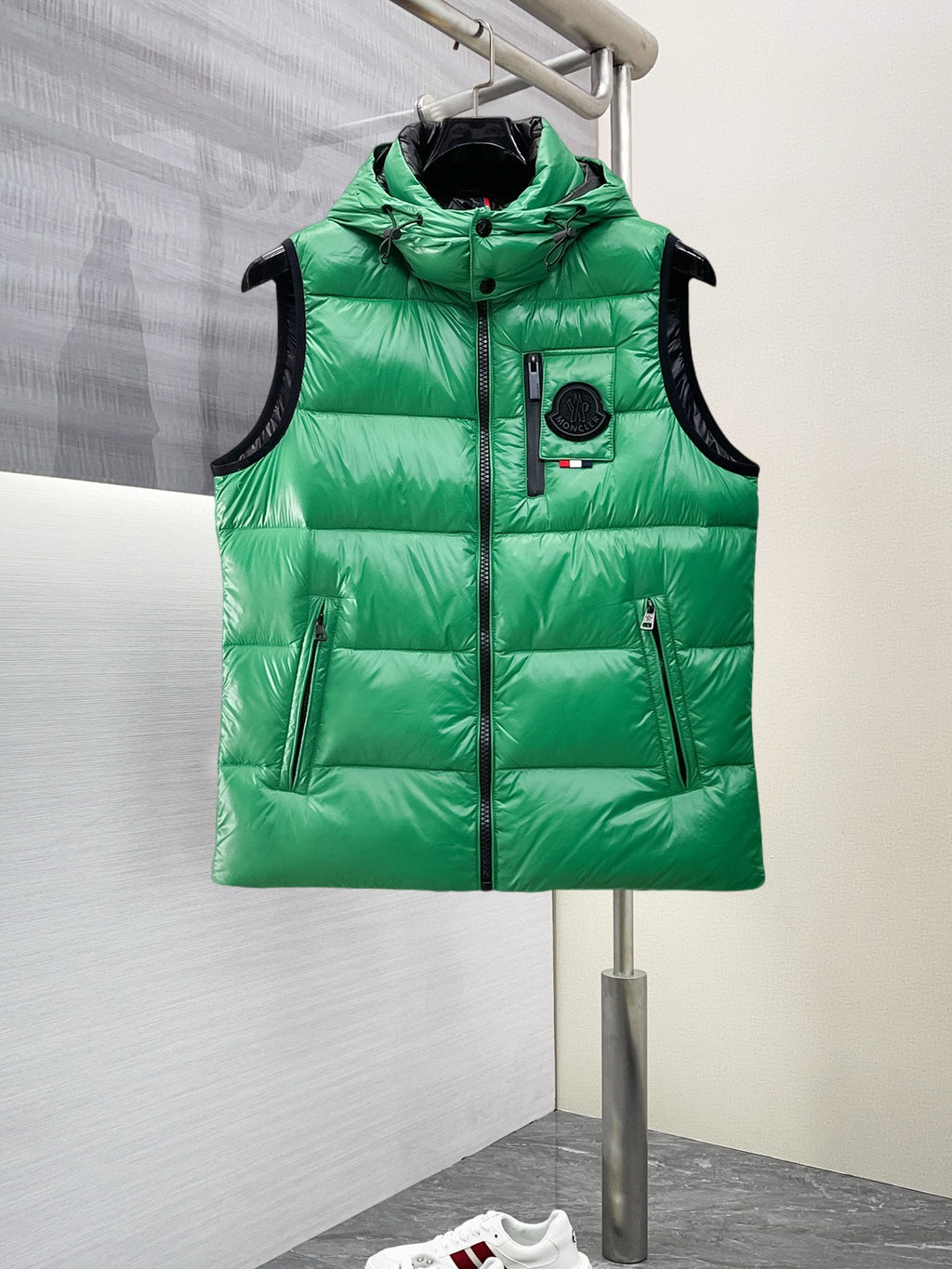 Green hooded puffer vest with black trim, front zipper, and side pockets