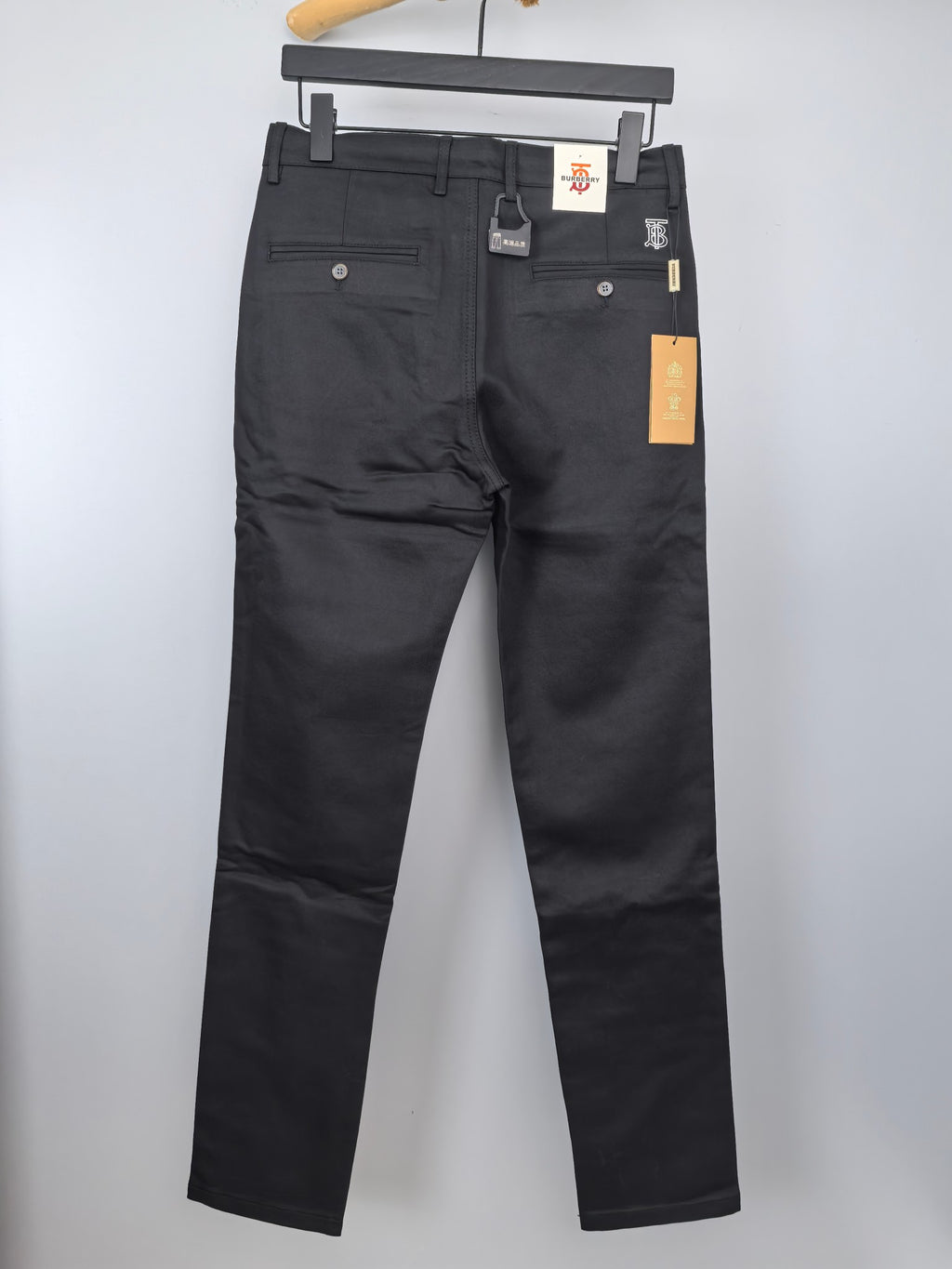 Black Burberry trousers on hanger, back view with pockets and small logo label