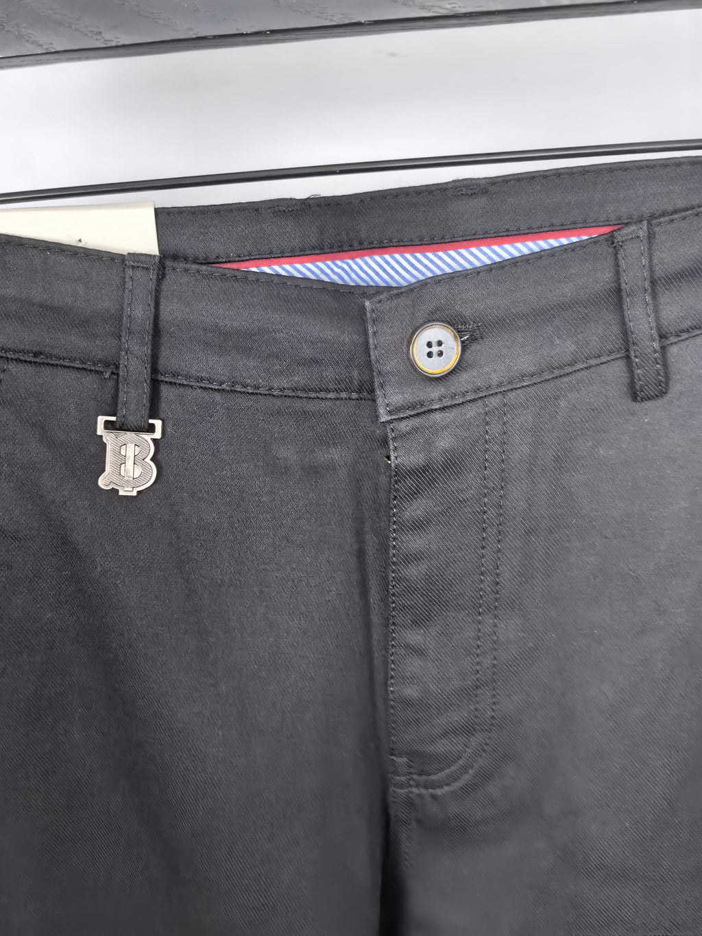 Black Burberry trouser waistband close-up with button and belt loop