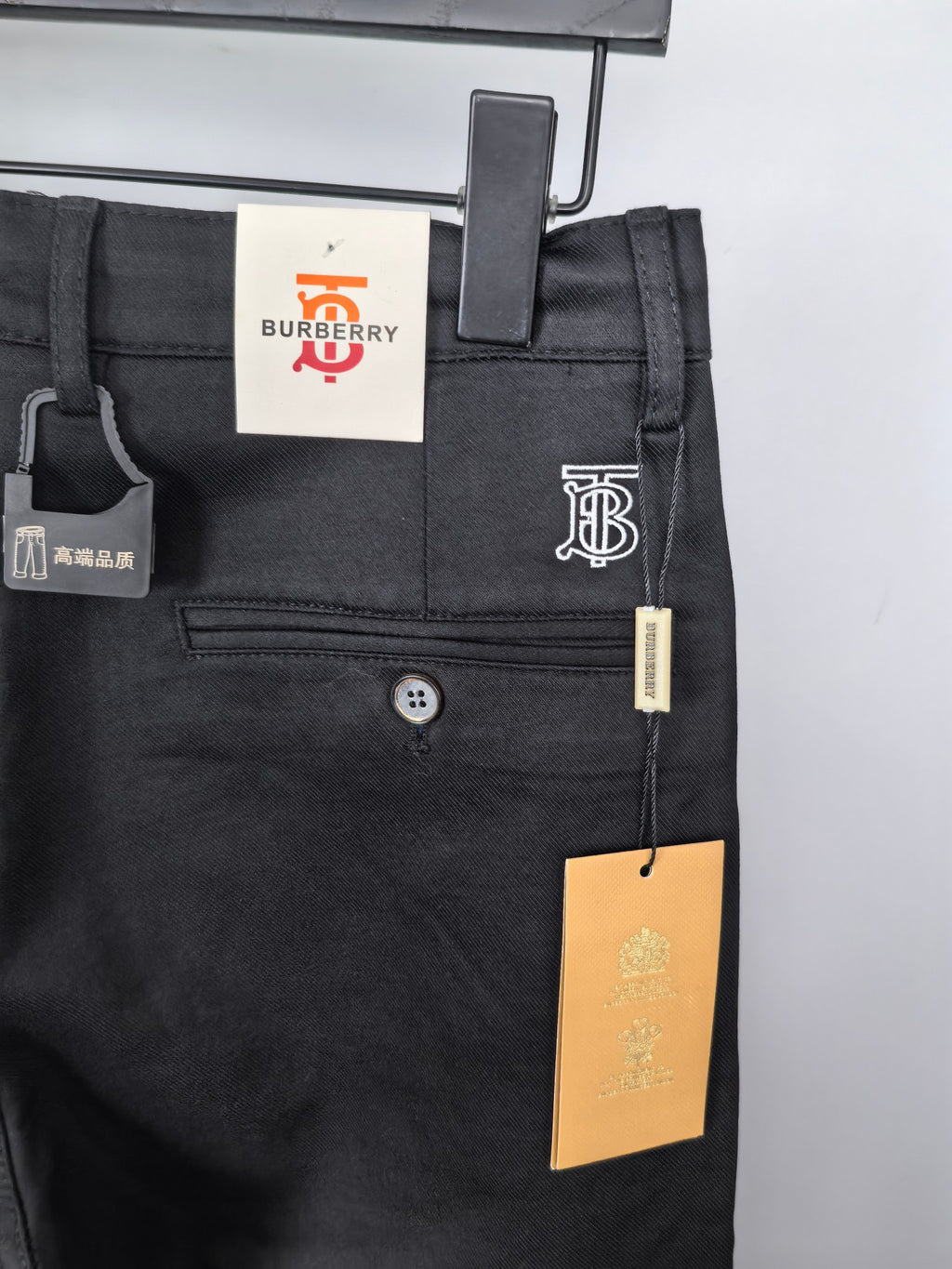 Black Burberry trousers front view with coin pocket, button, and tag