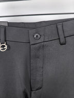 Waistband close-up with metal button and belt loop on black trousers