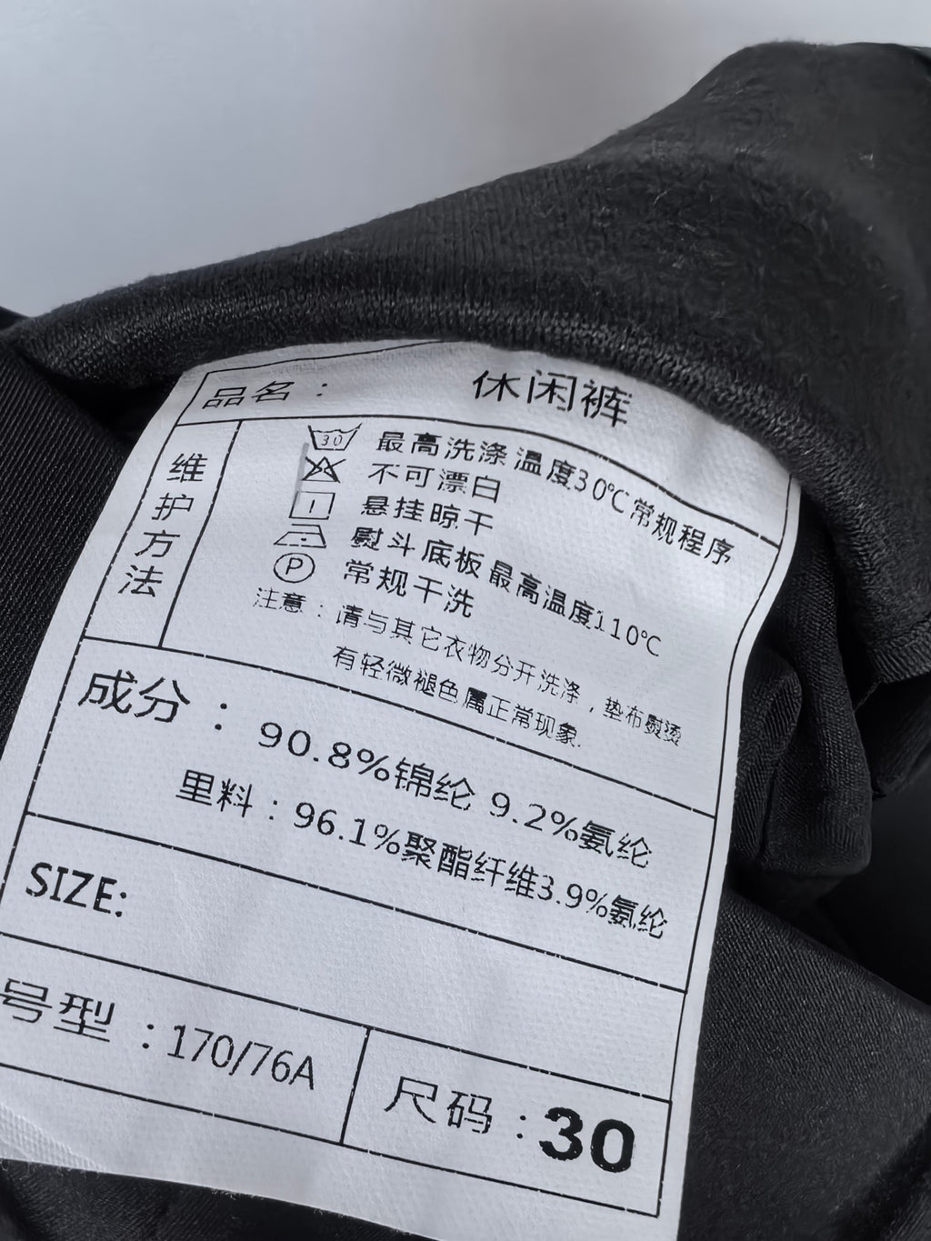 Black fabric care label and size tag showing size 30