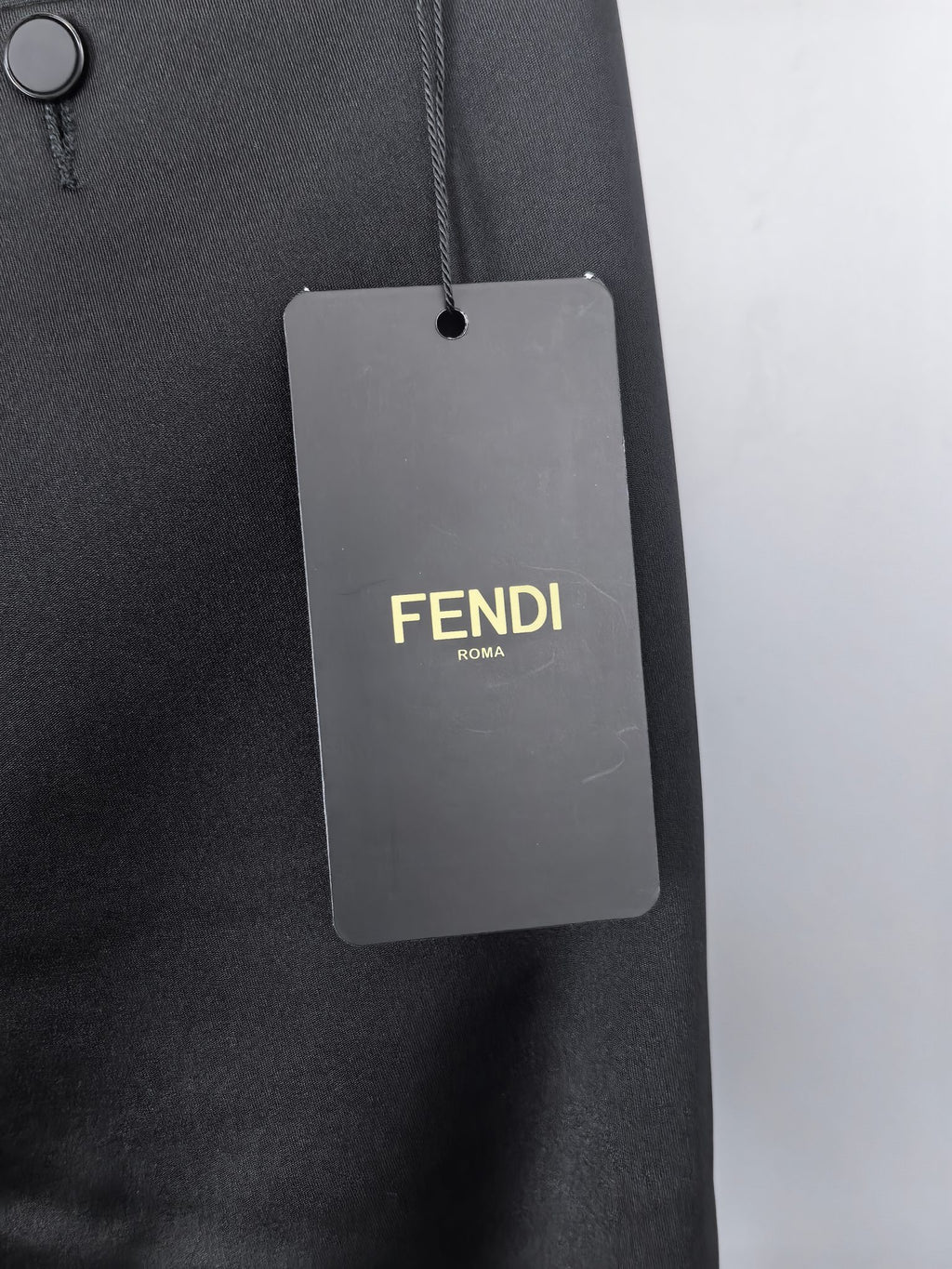 Black trousers with hanging FENDI ROMA size tag on belt loop