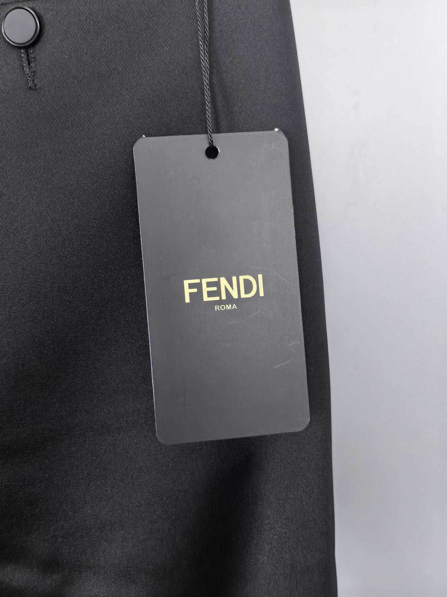 Black trousers with hanging FENDI ROMA size tag on belt loop