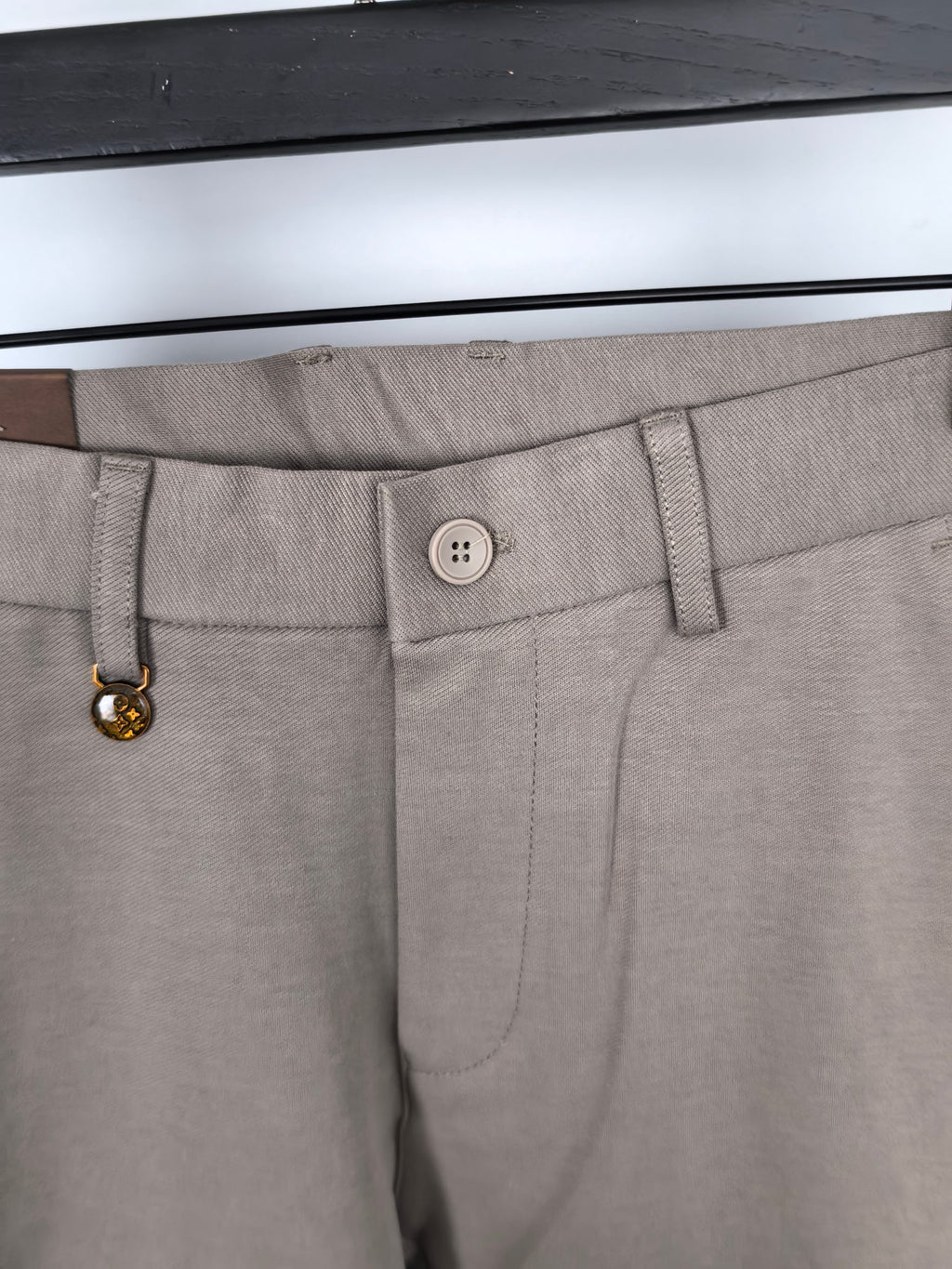 Beige pants waistband close-up with button and belt loop