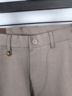 Beige pants waistband close-up with button and belt loop