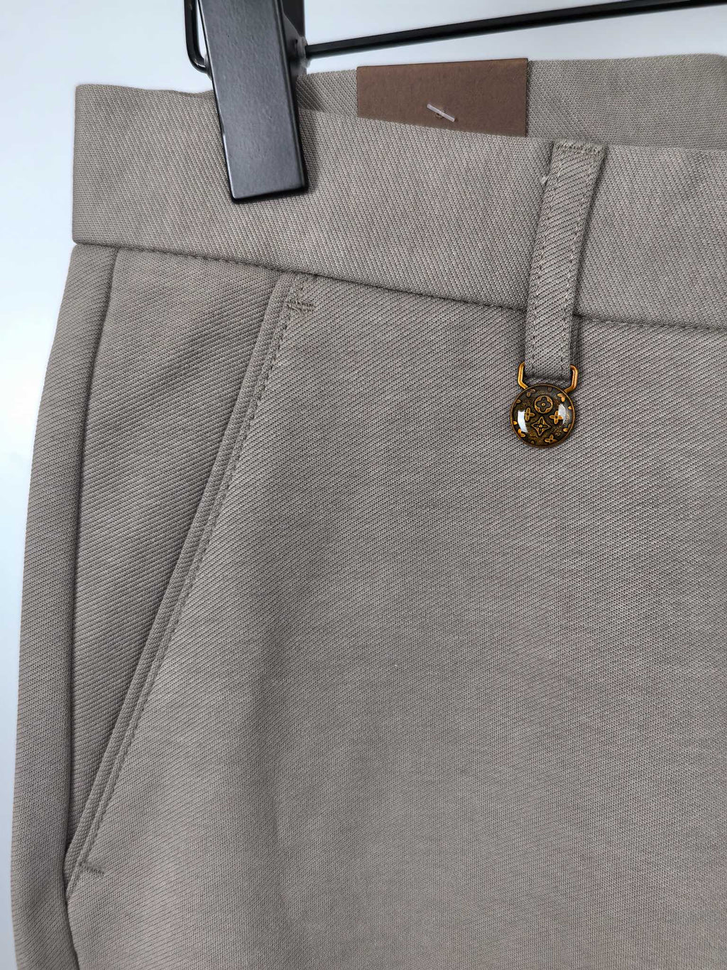 Beige pants waistband with side pocket seam and gold charm detail