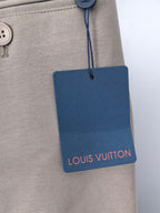 Beige pants with hanging Louis Vuitton tag and button at waistband