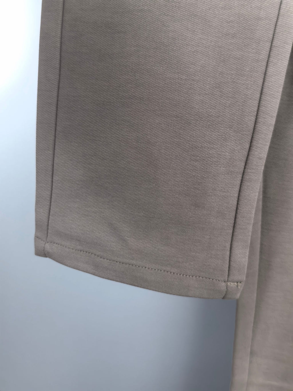 Beige pant hem close-up with straight stitching and side seam