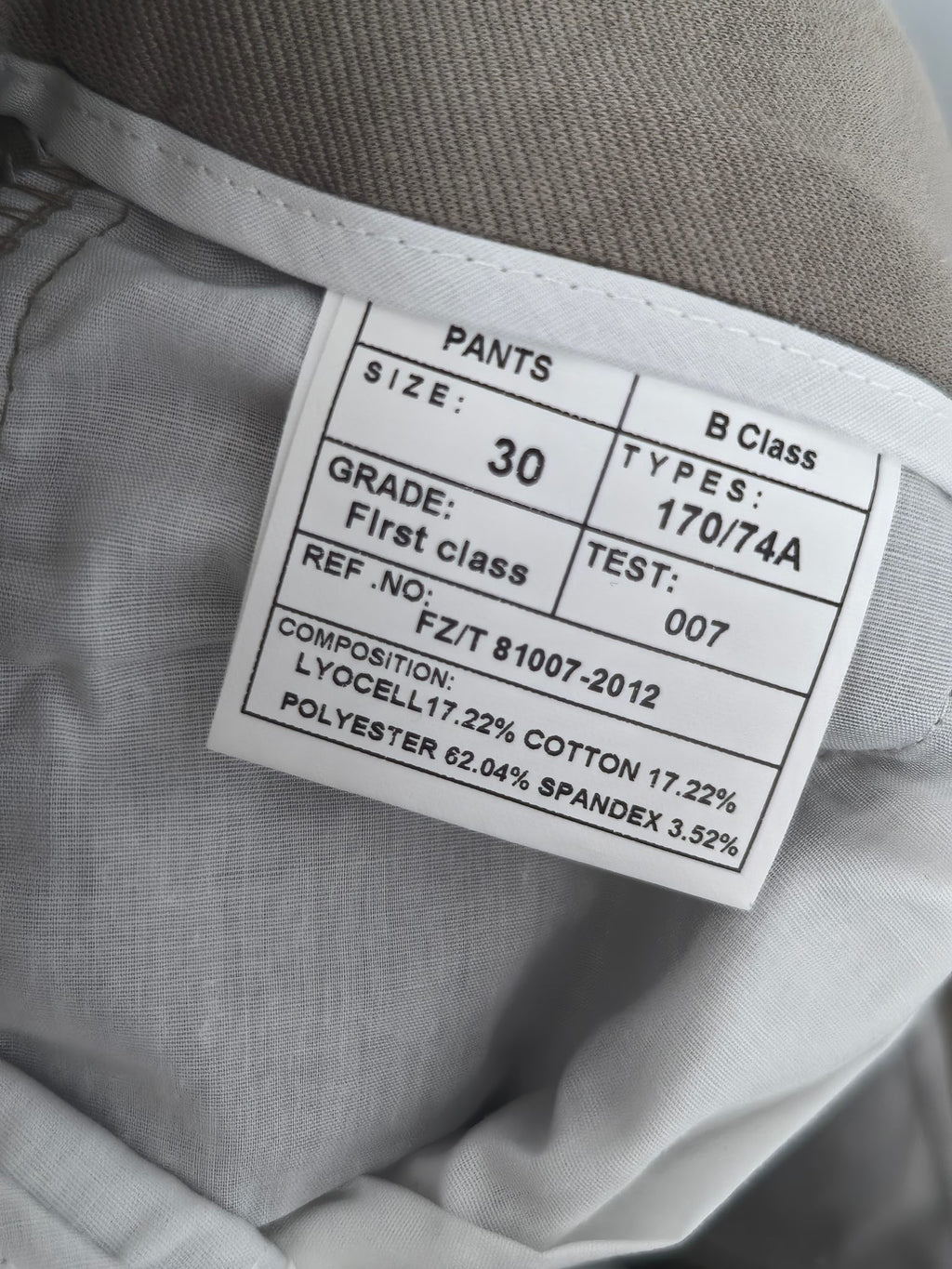 Beige pants size label showing PANTS, Class B, and composition percentages