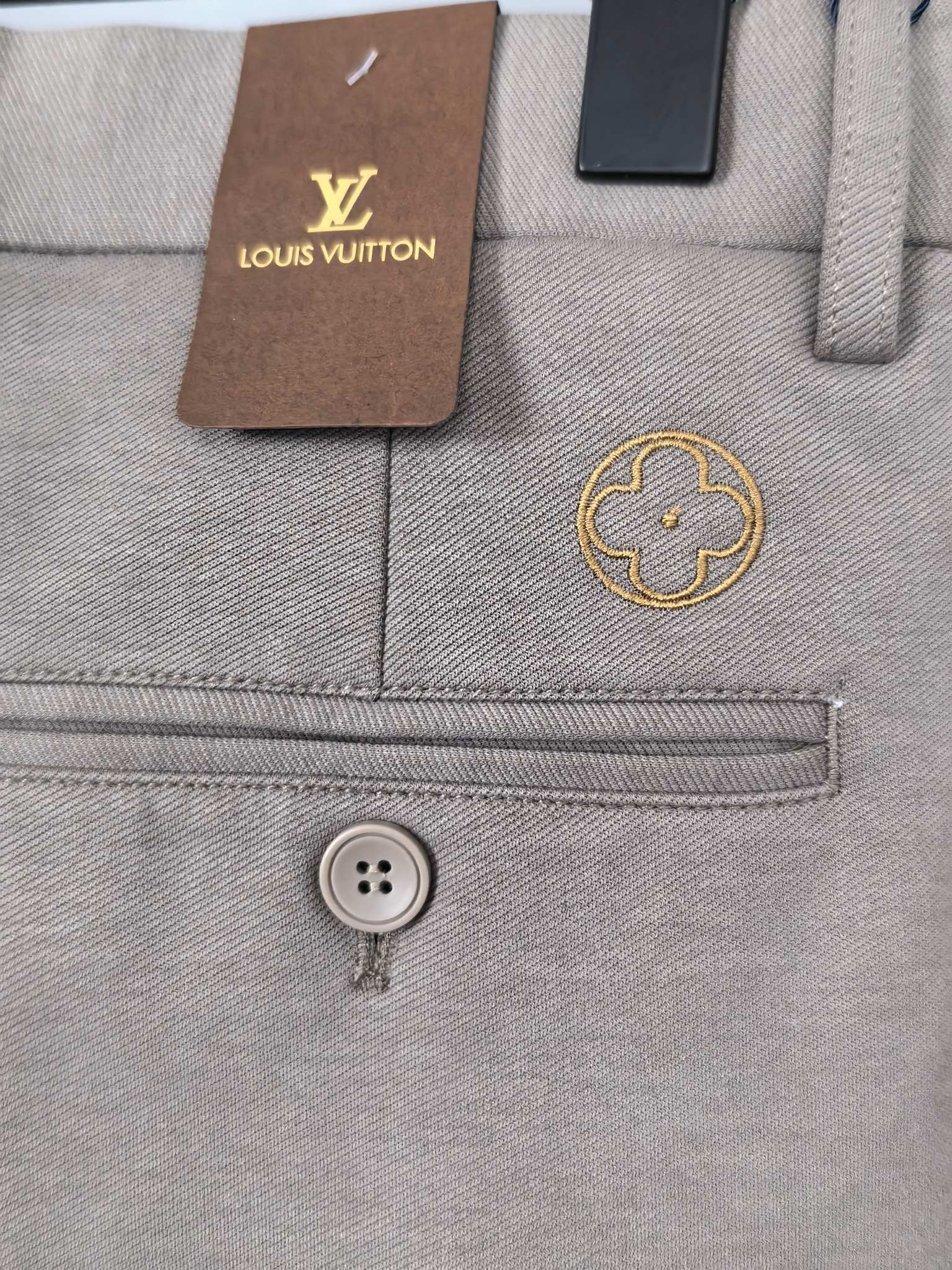 Beige pants detail with Louis Vuitton patch and button at waistband