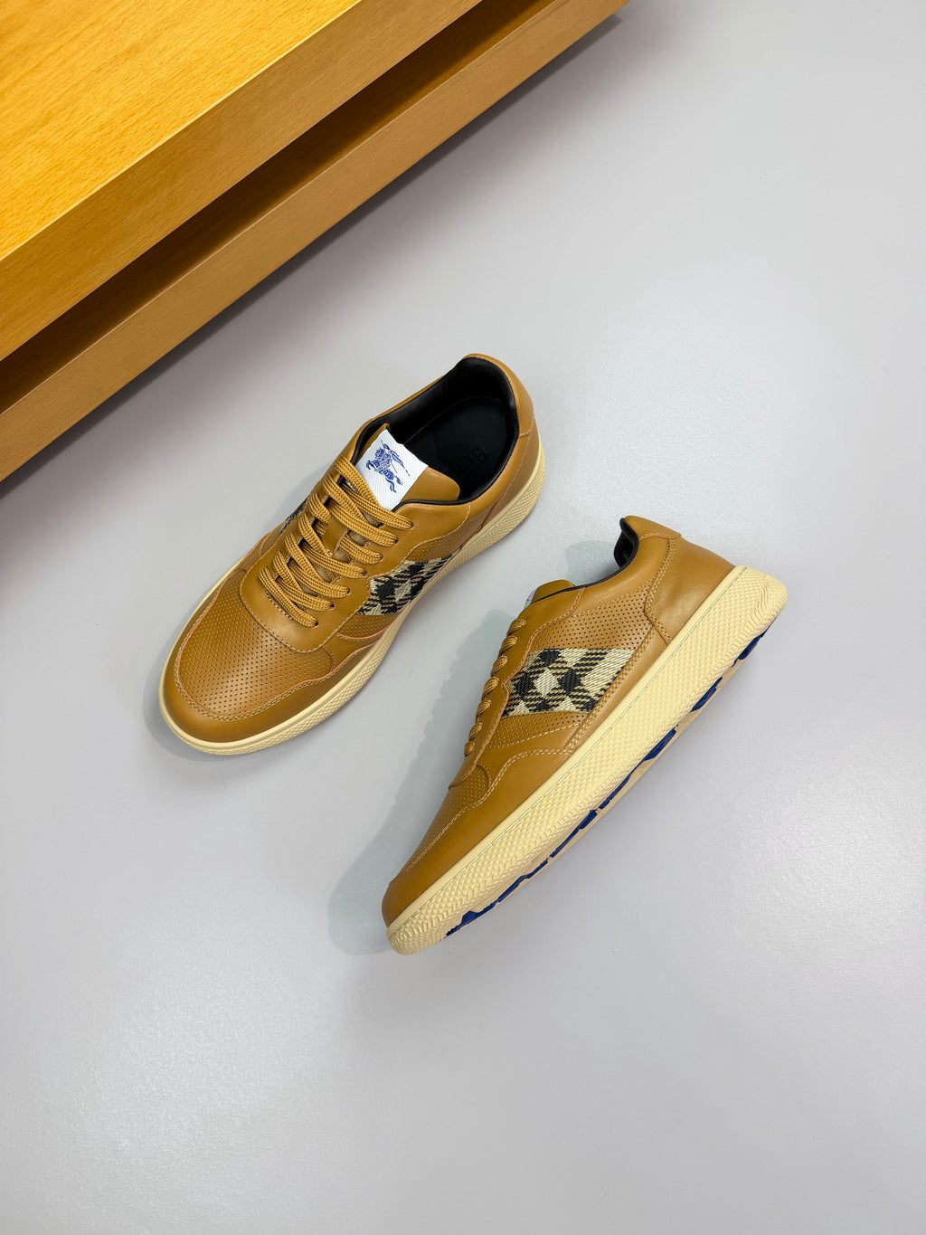 Pair of gold sneakers with lace-up front, Burberry check inset, and off-white sole