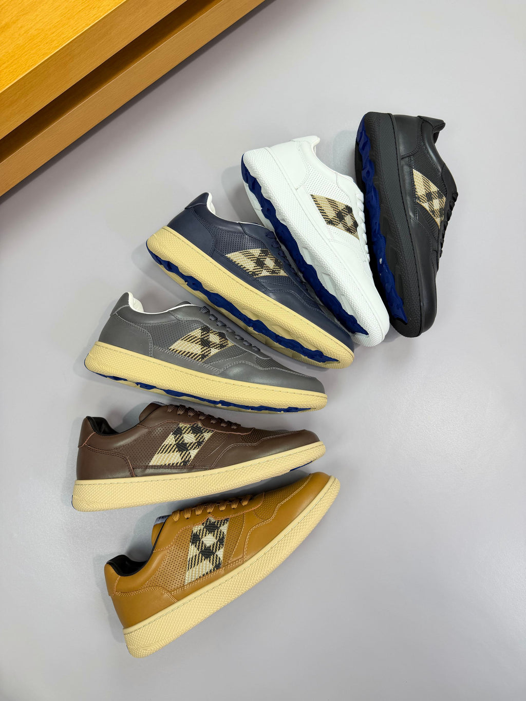 Sneakers assortment with gold, navy, and grey uppers and Burberry check side panels