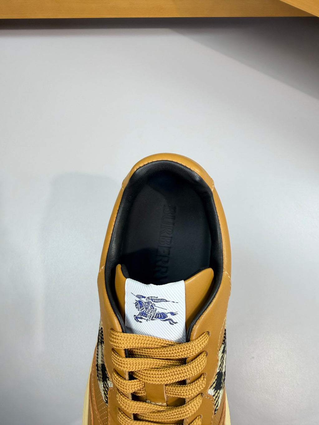 Sneaker heel and lace area with gold upper, dark collar, and Burberry check lining