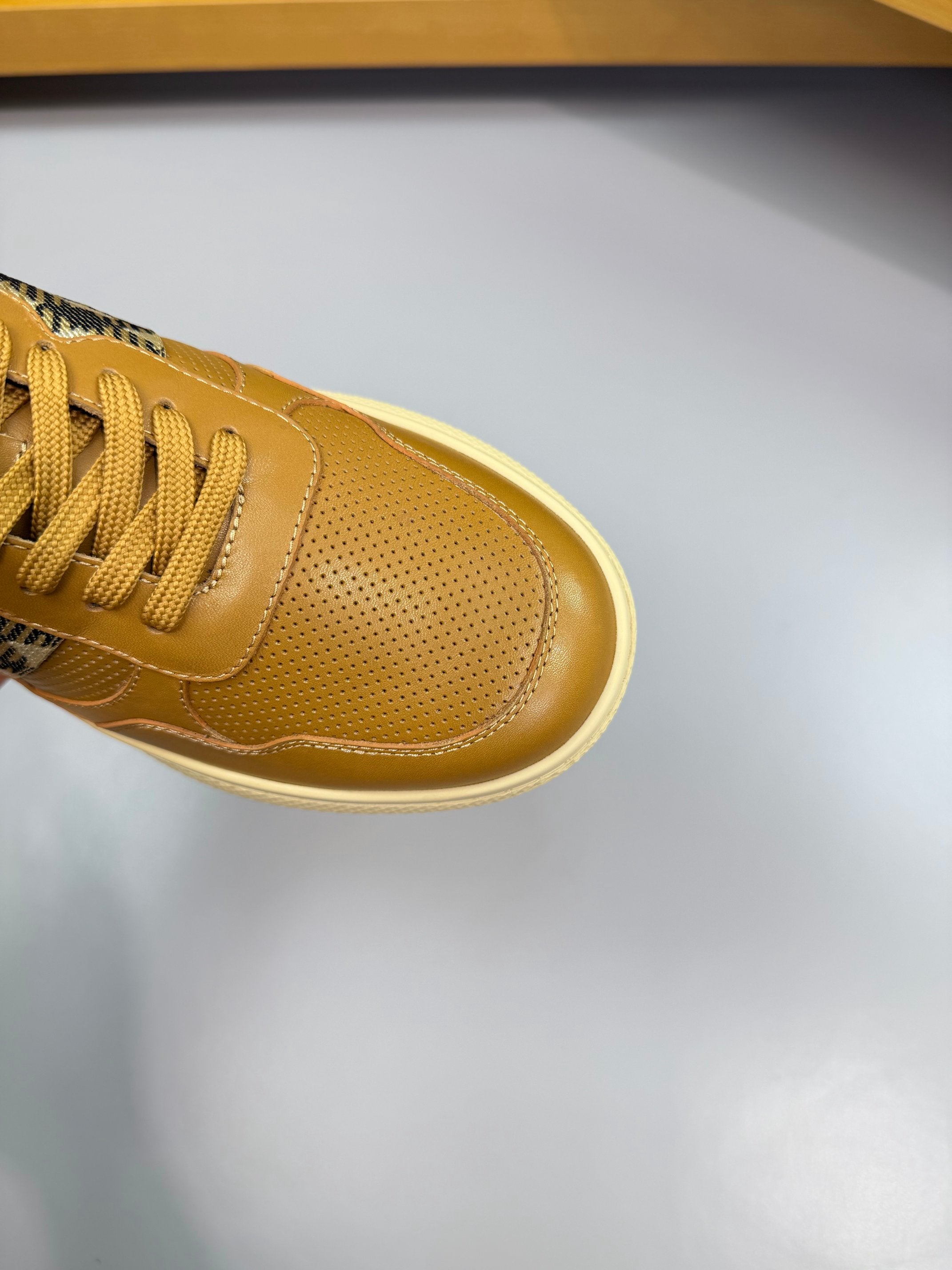 Close-up of gold sneaker toe and laces with Burberry check side insert