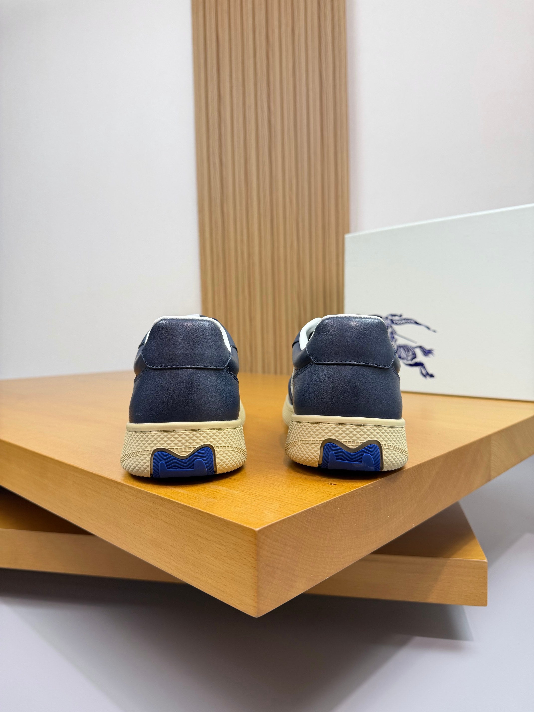 Pair of Burberry low-top sneakers from the back in navy with blue-tinted soles