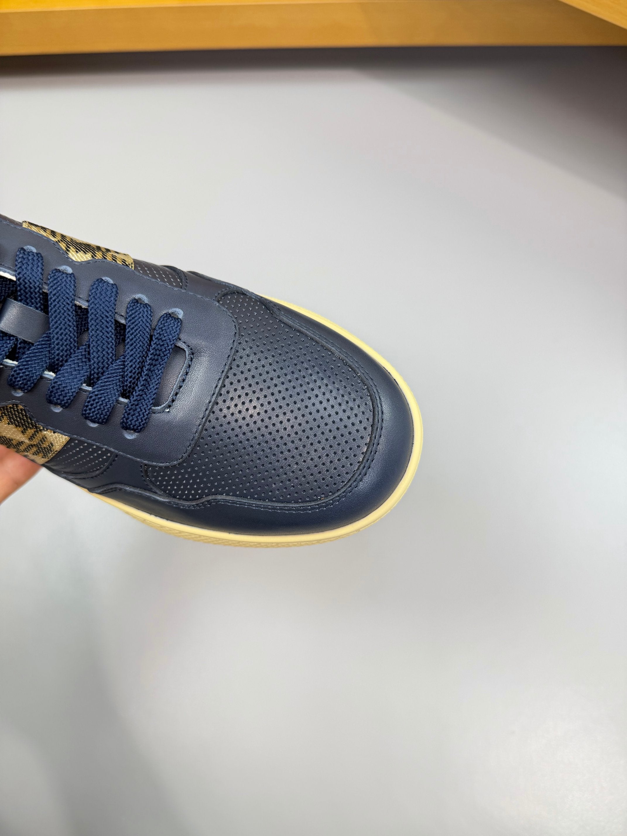 Burberry low-top sneaker close-up in navy with check strap and yellow trim